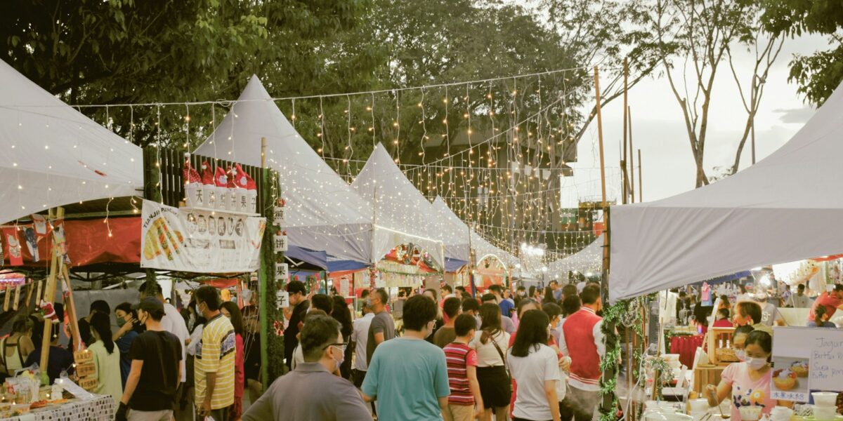Outdoor market vendors with people browsing merchandise stalls
